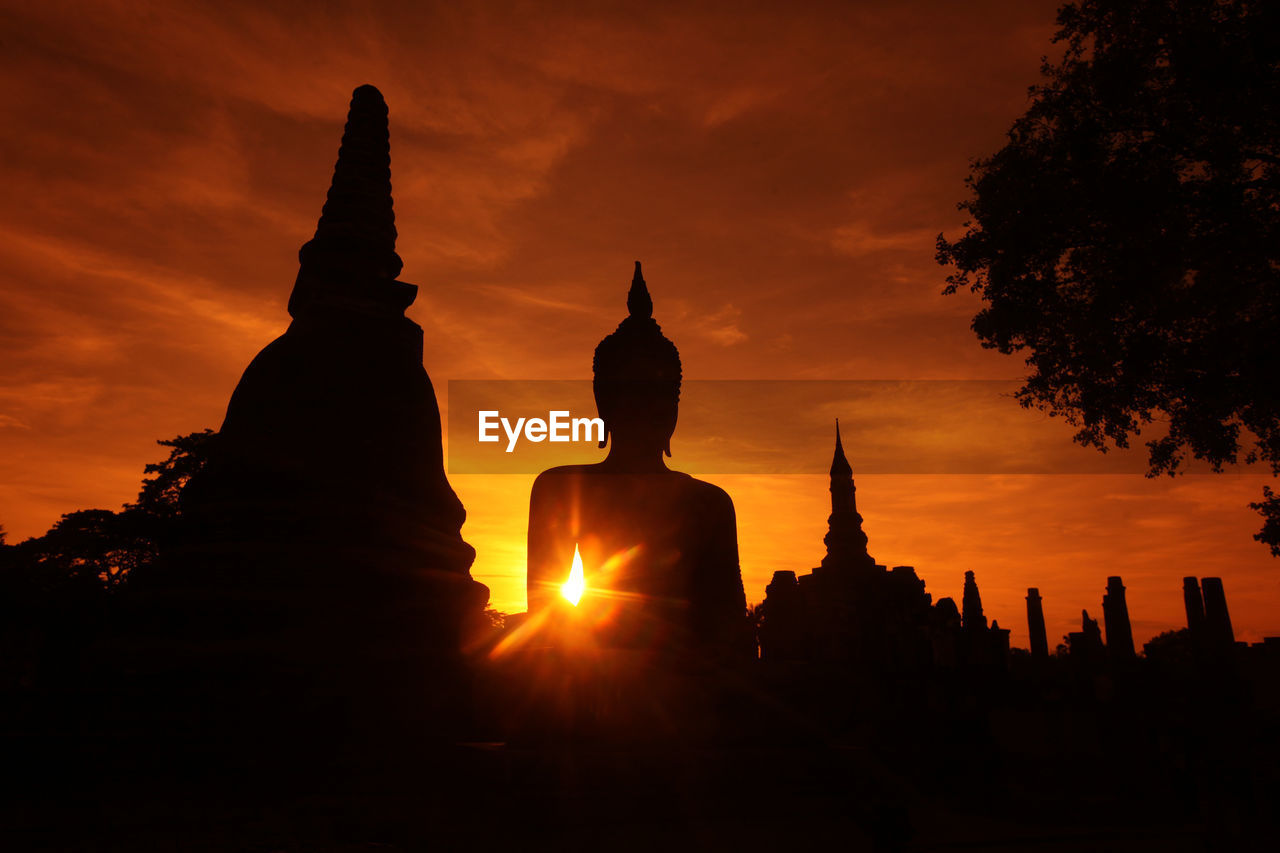 SILHOUETTE OF BUDDHA STATUE AGAINST SKY DURING SUNSET