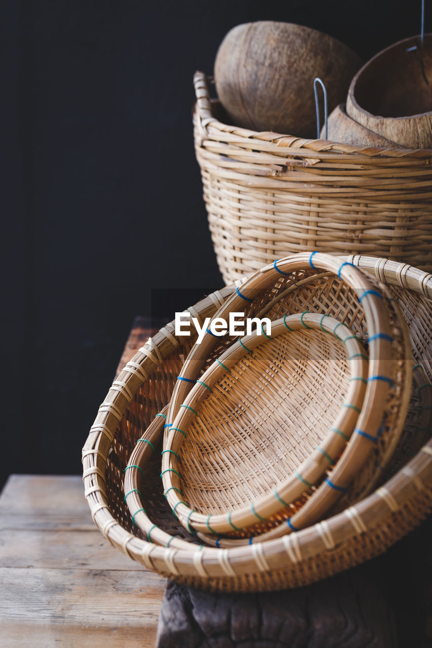 Close-up of wicker baskets on table against black background