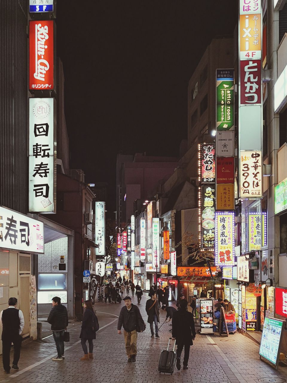 PEOPLE WALKING ON ILLUMINATED STREET MARKET