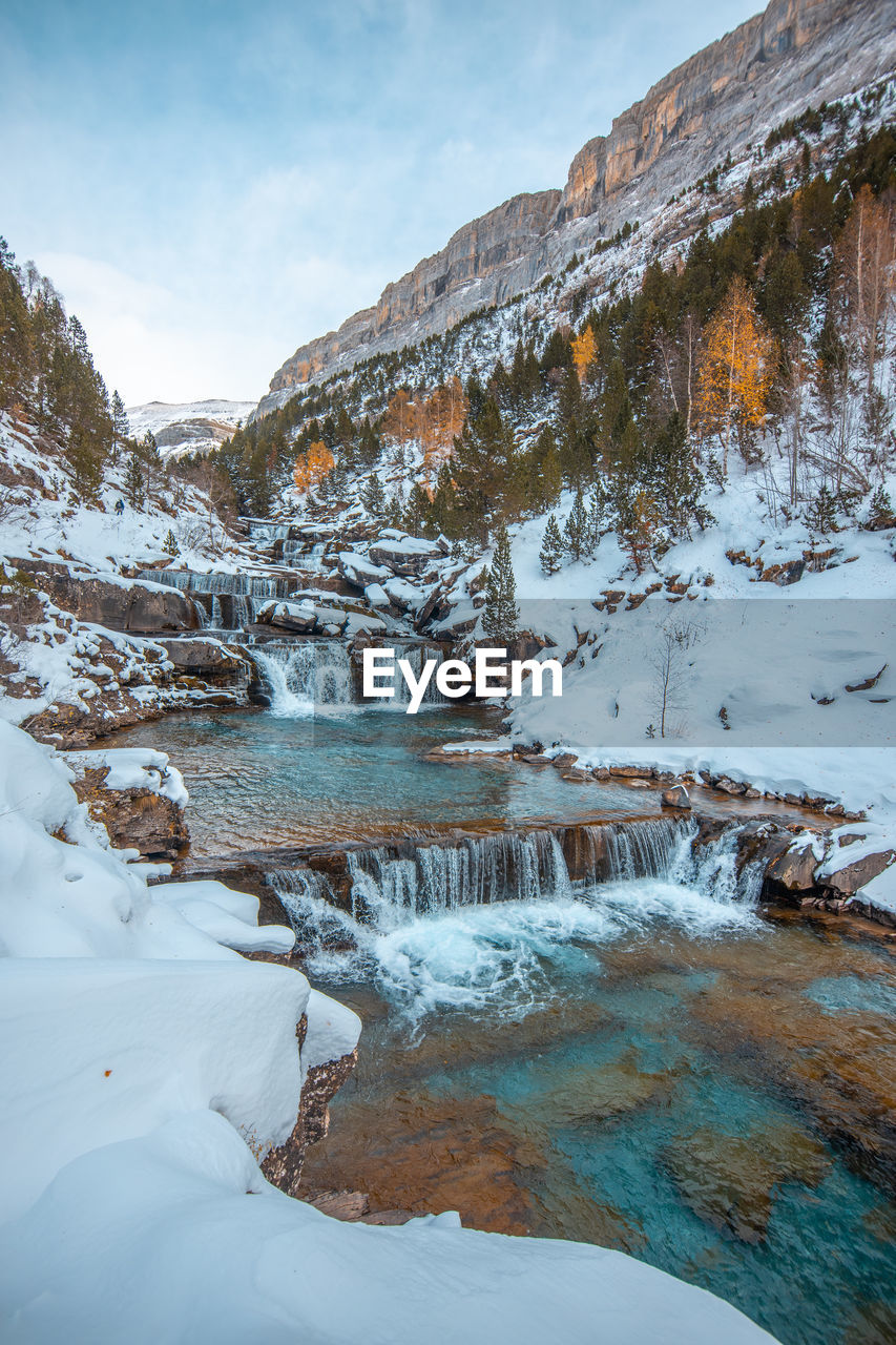 Frozen lake by snowcapped mountain against sky