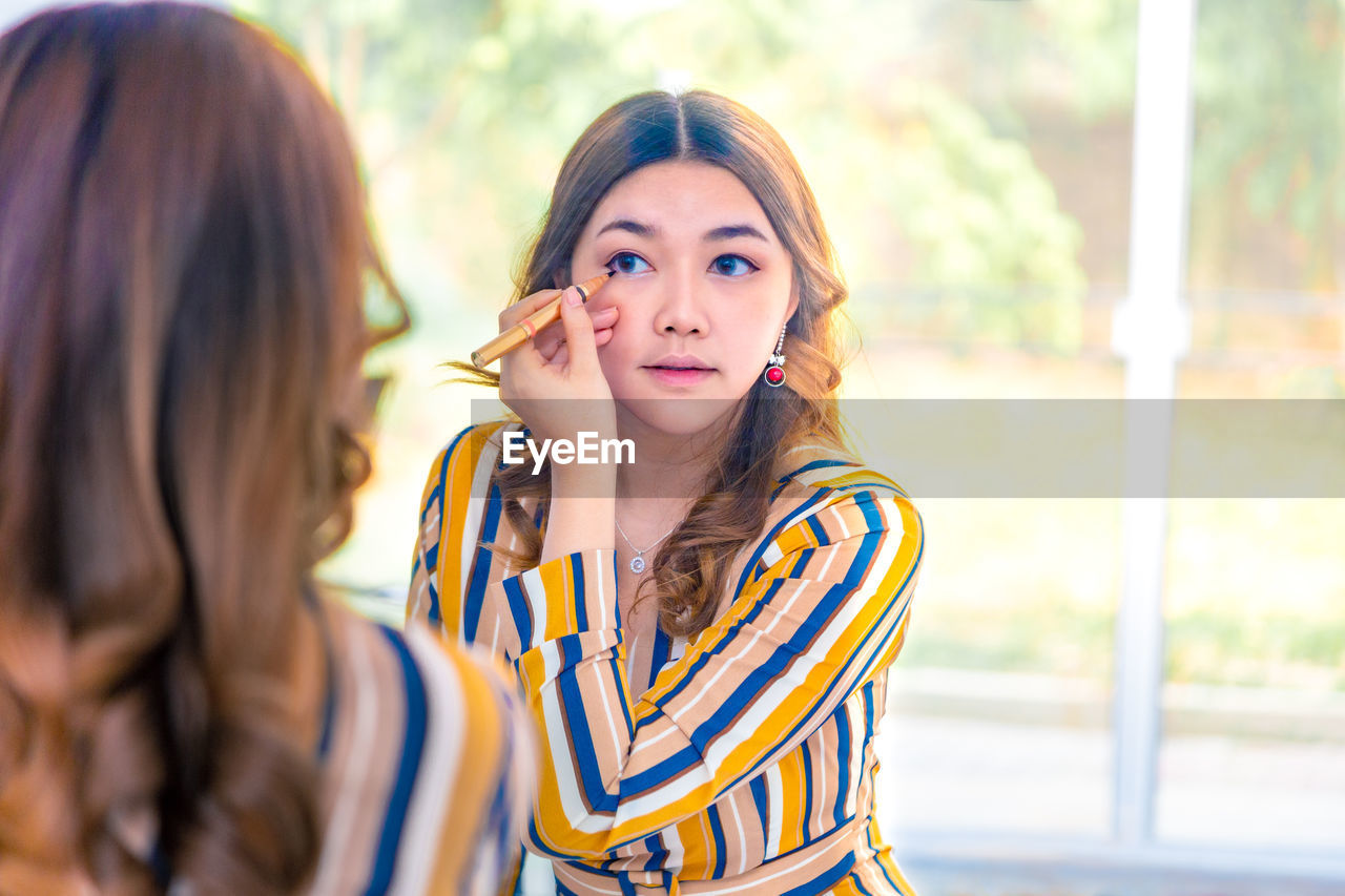 Woman applying mascara at home