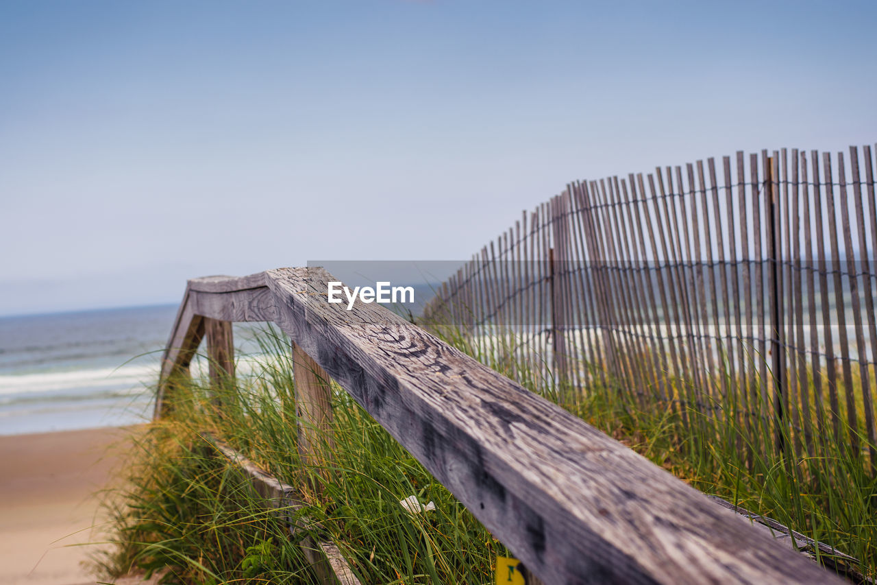 Wooden fence on beach against clear sky