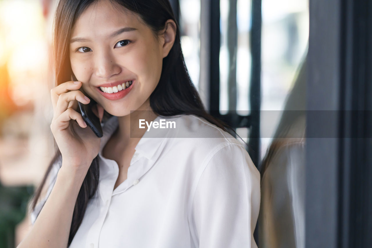 Portrait of smiling young woman using mobile phone