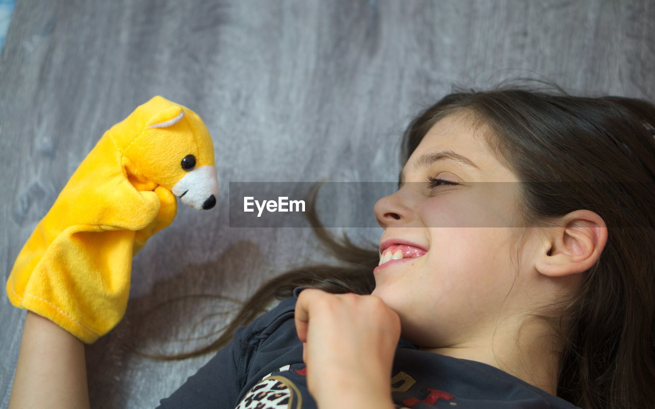 High angle view of girl playing with toy while lying on floor