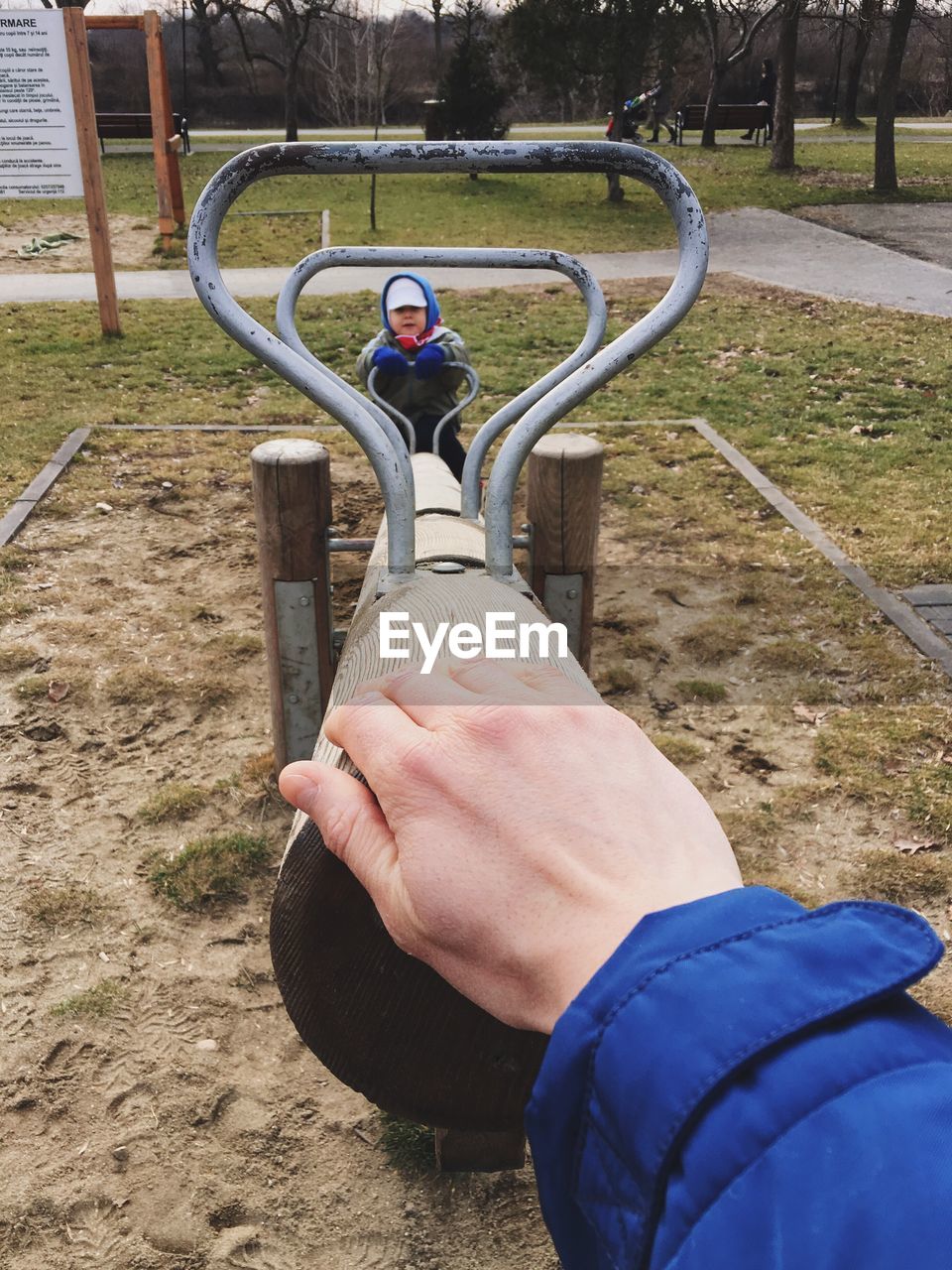 Cropped hand of person touching seesaw in park