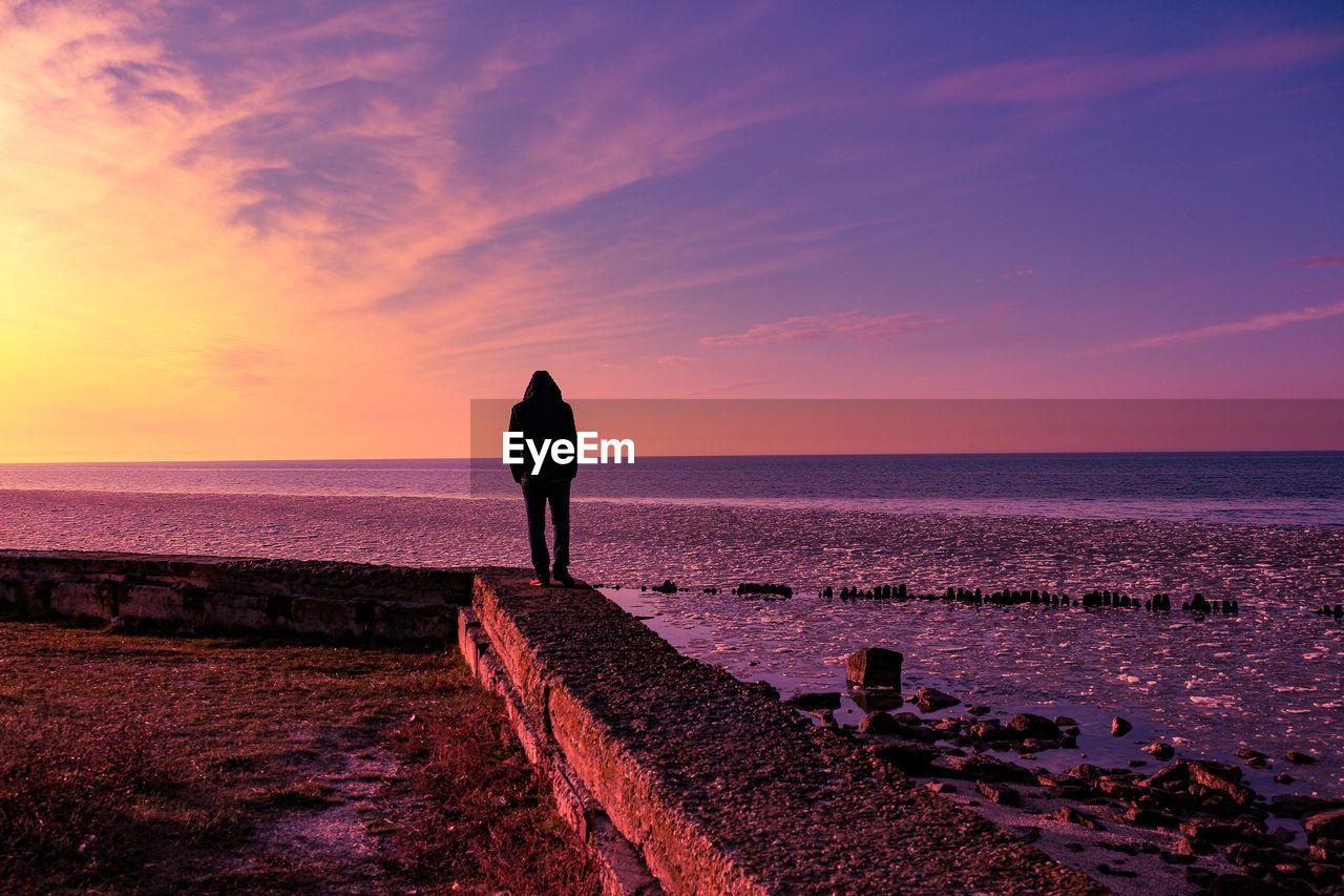 Man looking at sea against sky during sunset