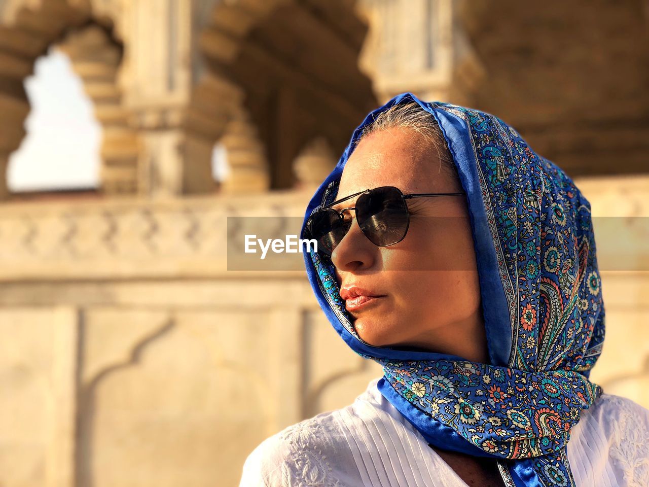 Woman wearing scarf while standing against historic building