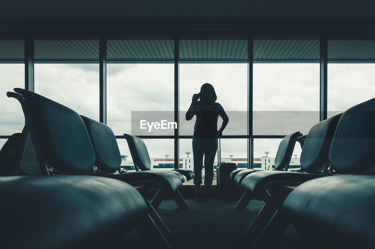 Rear view of woman standing at airport departure area