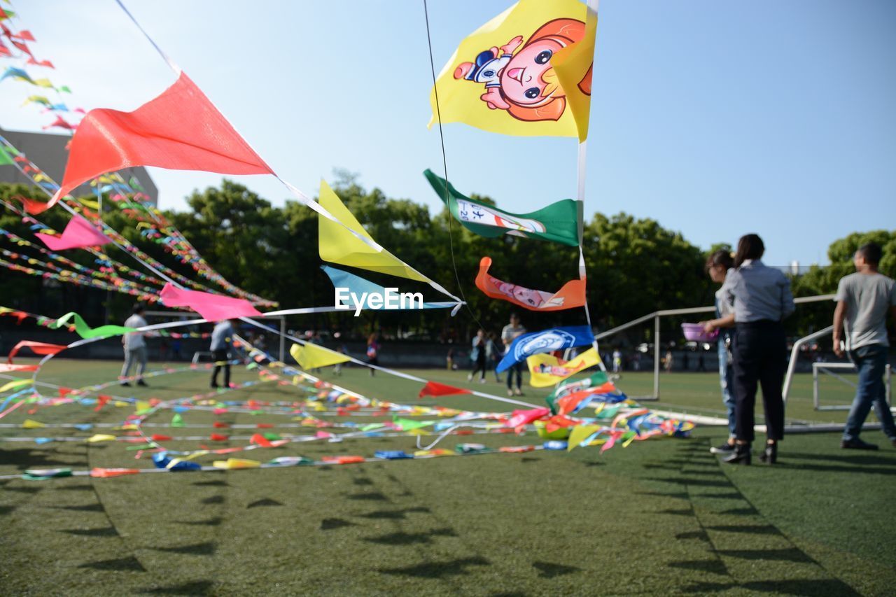 Colorful flags waving on playing field against sky