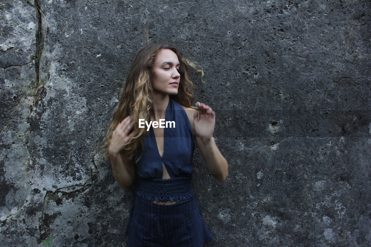 Portrait of young woman standing against wall