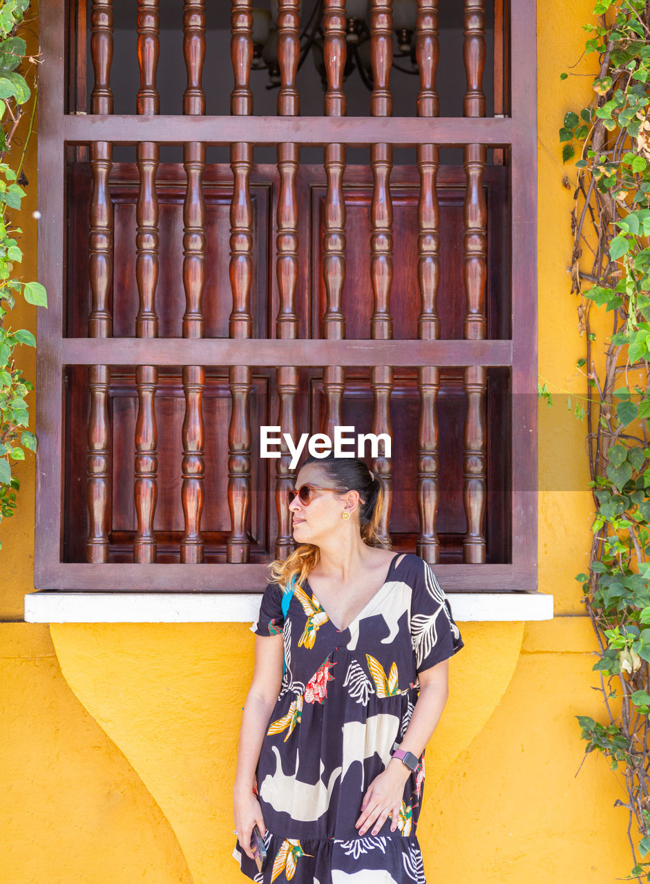 side view of young woman standing against old building