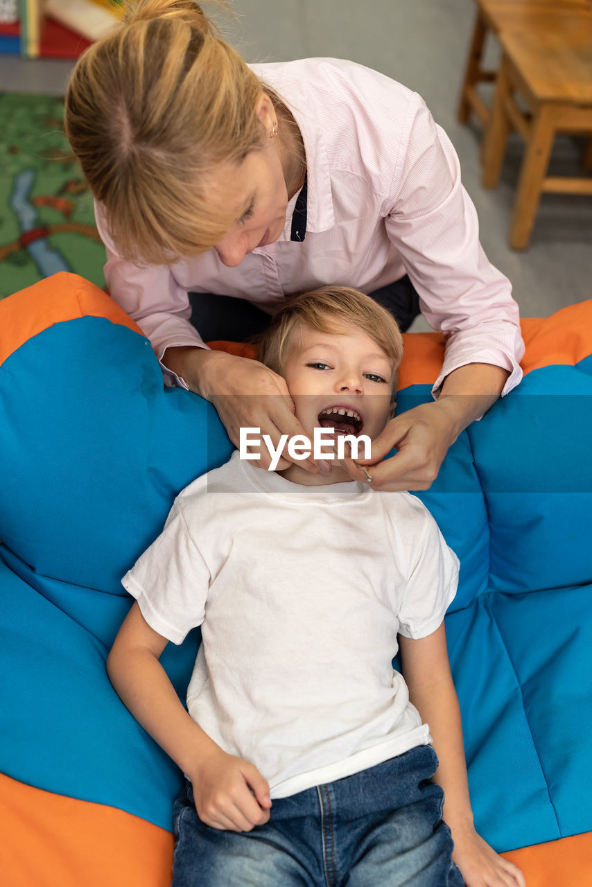 high angle view of mother and daughter sitting on bed at home