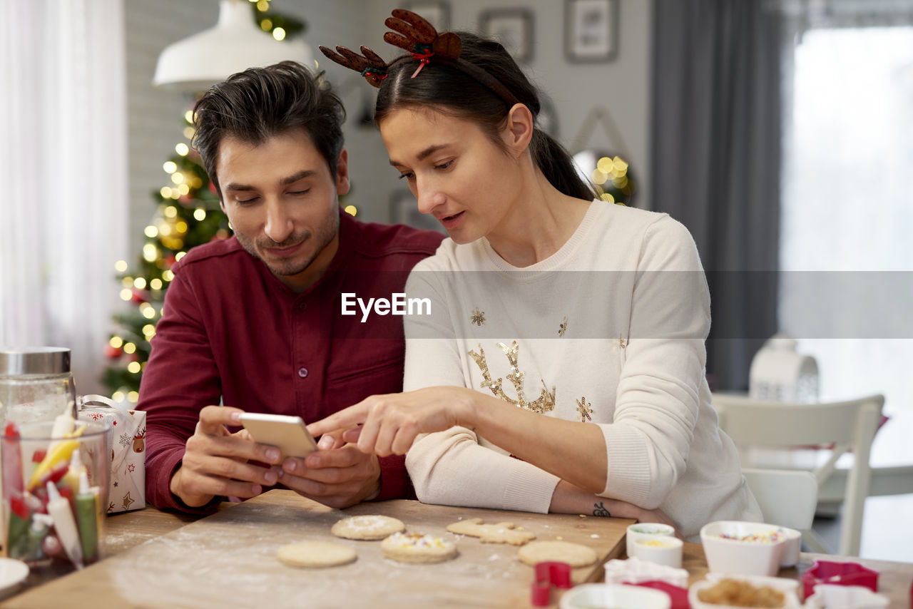 Couple looking at mobile phone while enjoying christmas 