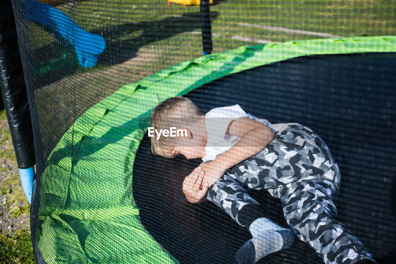 Injured boy lying on trampoline at jungle gym 