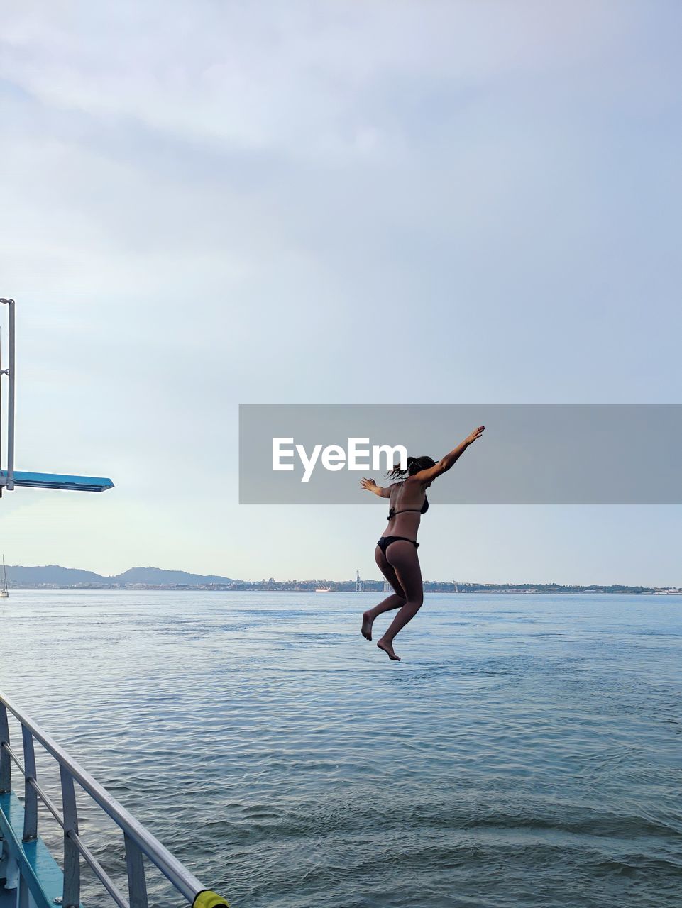 Man jumping in sea against sky