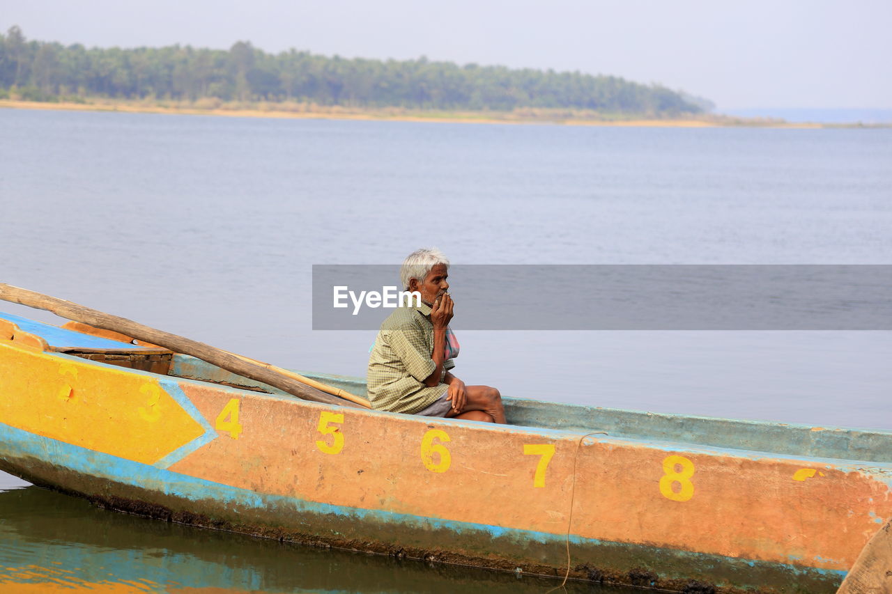 Side view of senior man sitting in boat at sea