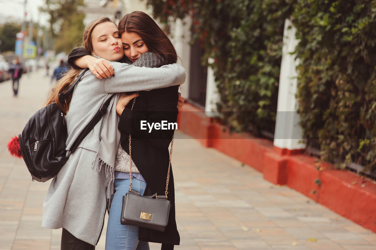 Friends embracing on footpath