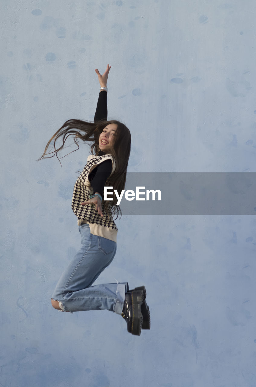 Low section of woman jumping against wall