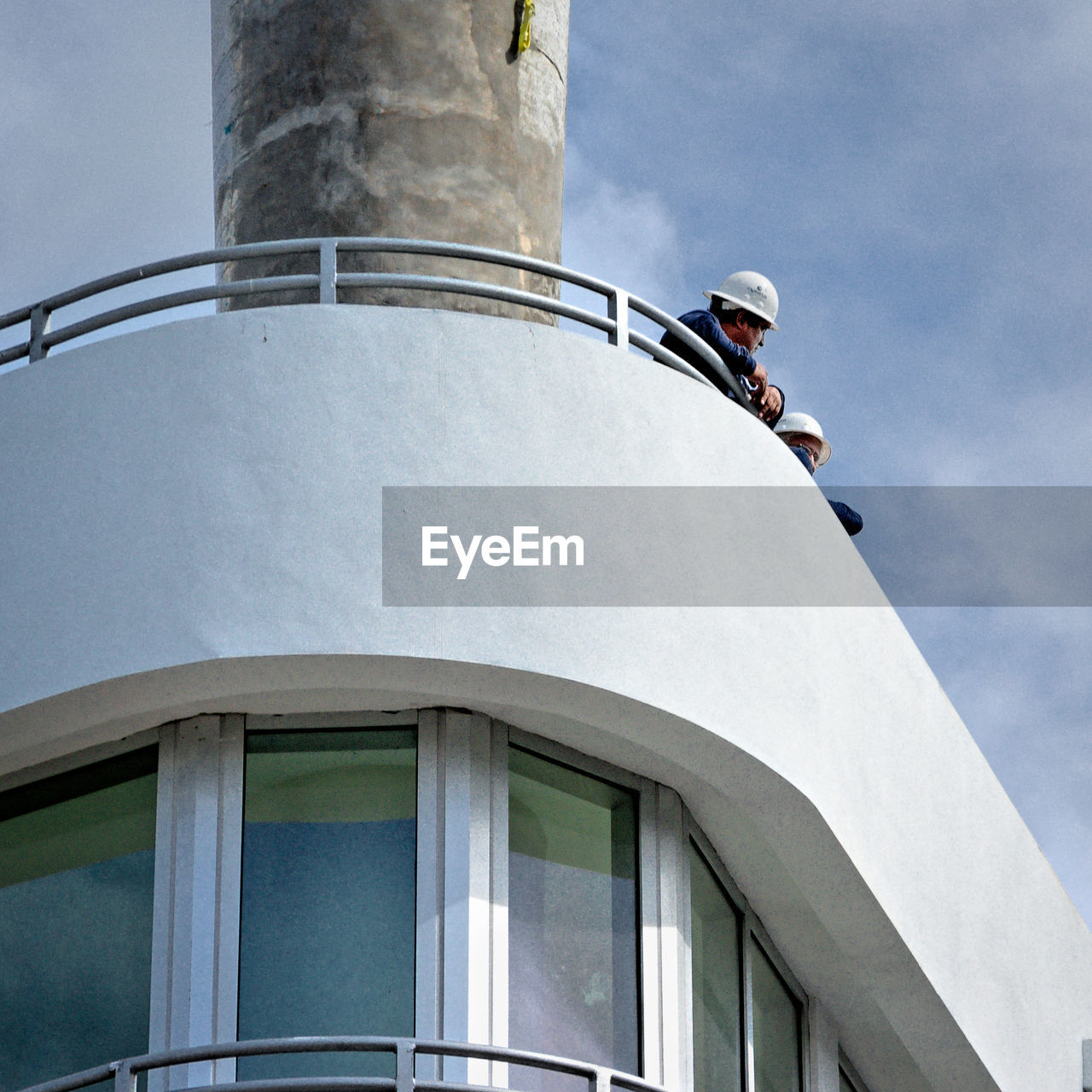 LOW ANGLE VIEW OF MAN STANDING BY BUILDING