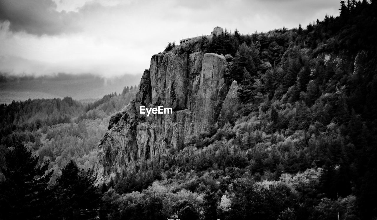 Rocky mountain amidst trees against sky