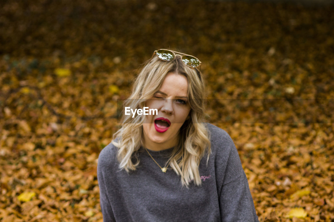 Portrait of woman winking agaisnt autumn leaves