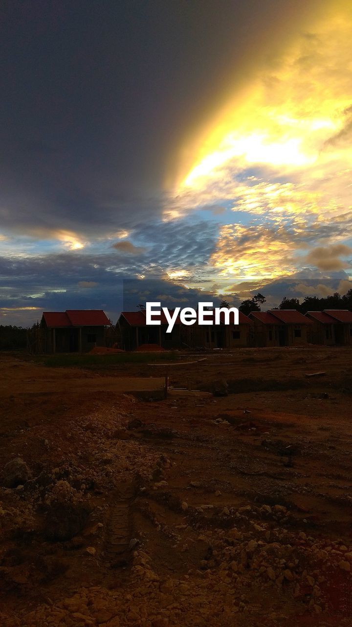 HOUSES ON FIELD AGAINST SKY DURING SUNSET