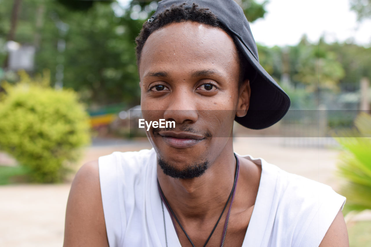 Close-up portrait of smiling young man wearing cap