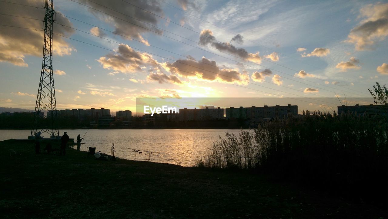 Buildings by lake against sky at sunrise