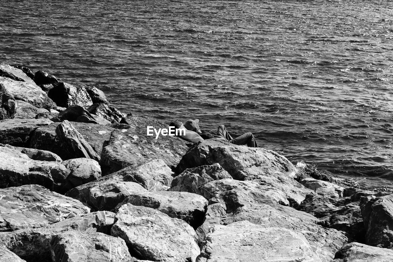 High angle view of man resting on rocks at sea shore