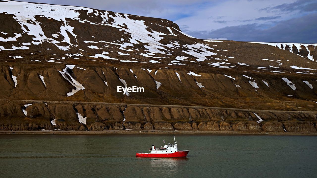 SCENIC VIEW OF SEA BY SNOWCAPPED MOUNTAIN