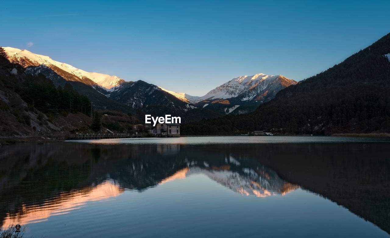 Scenic view of lake by mountains against sky during winter