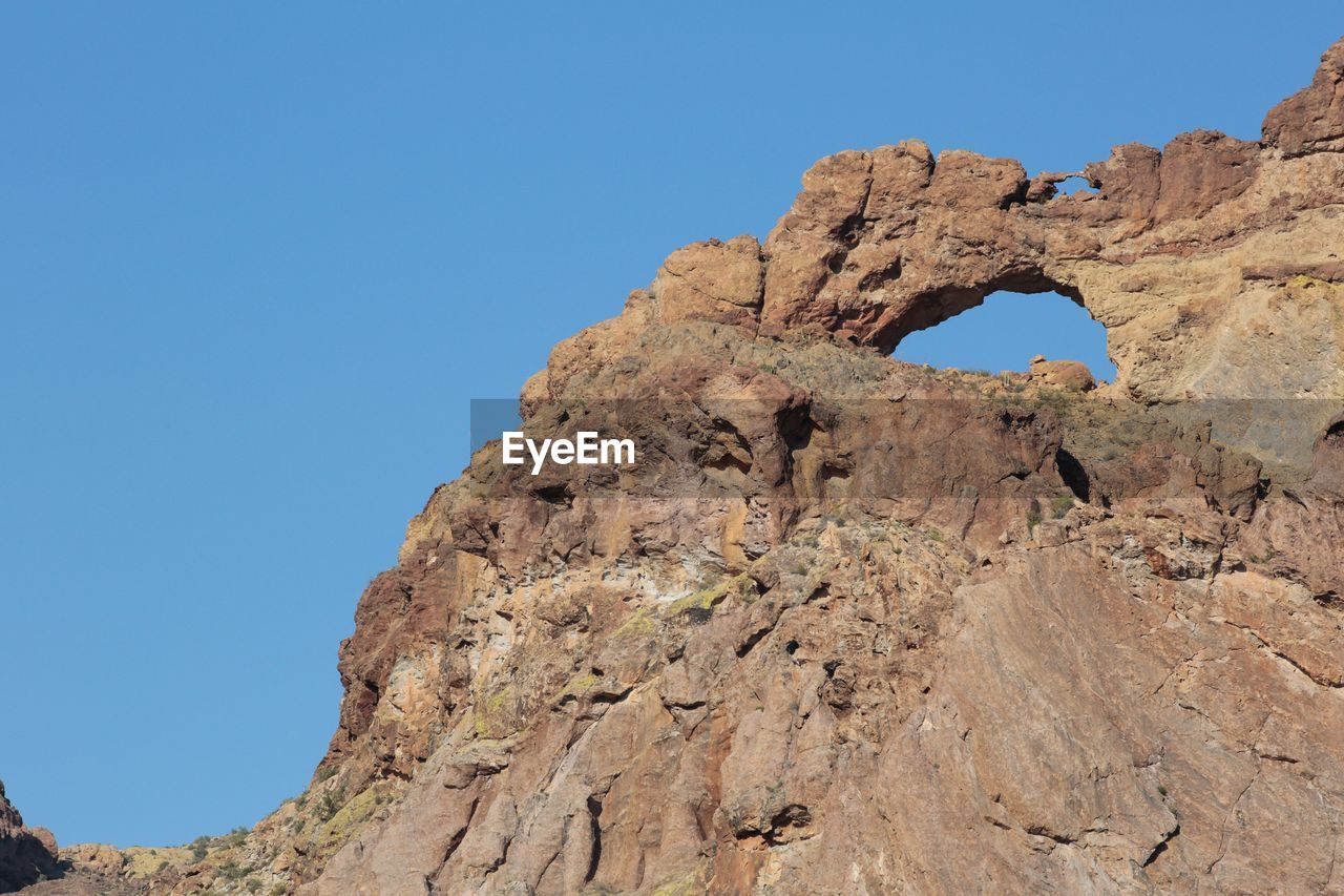 LOW ANGLE VIEW OF ROCK FORMATIONS AGAINST BLUE SKY