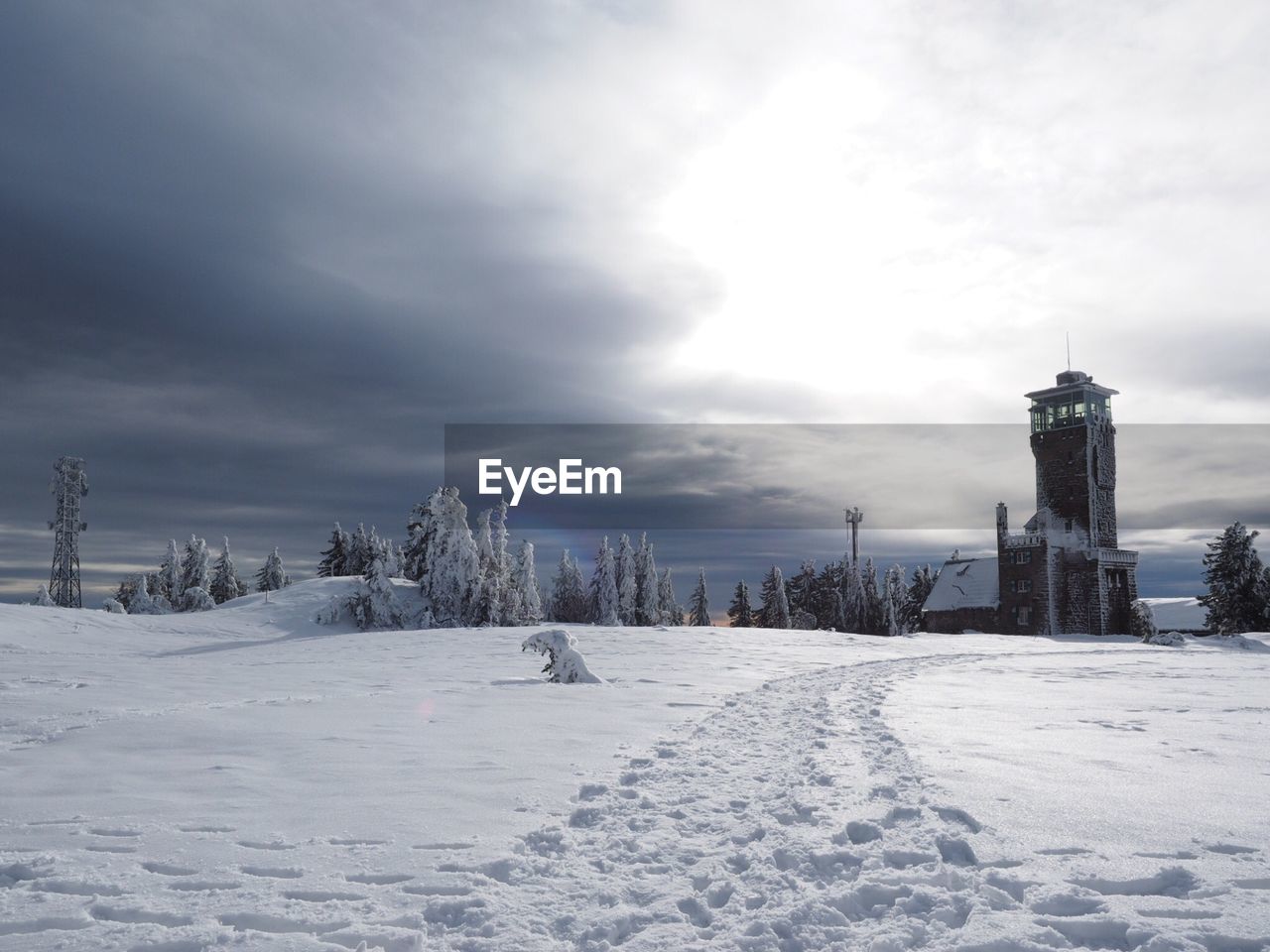 Scenic view of snow covered field against cloudy sky