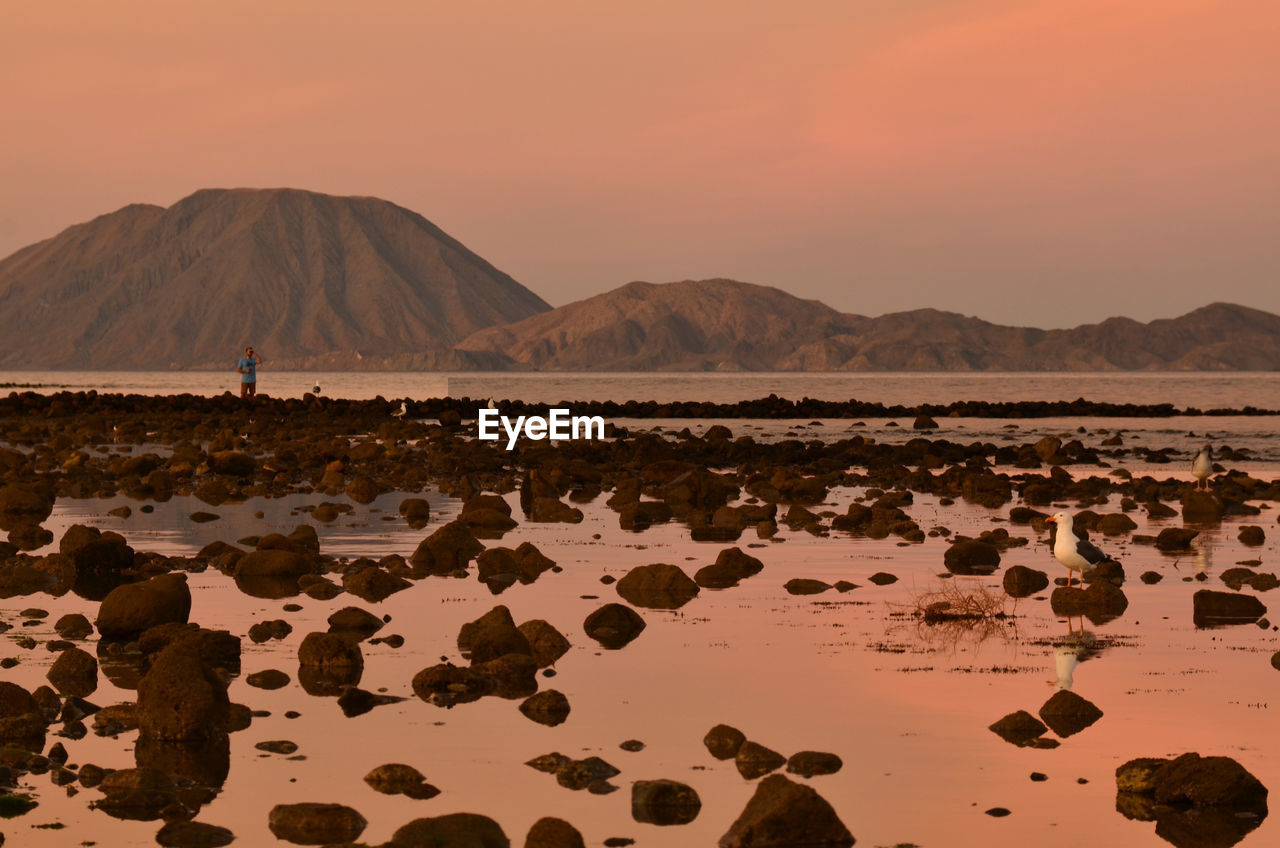 Scenic view of sea against mountains during sunset