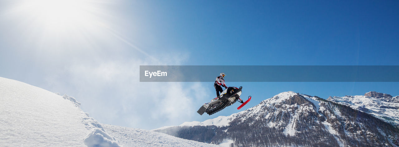 MAN SKIING ON SNOWCAPPED MOUNTAIN AGAINST SKY