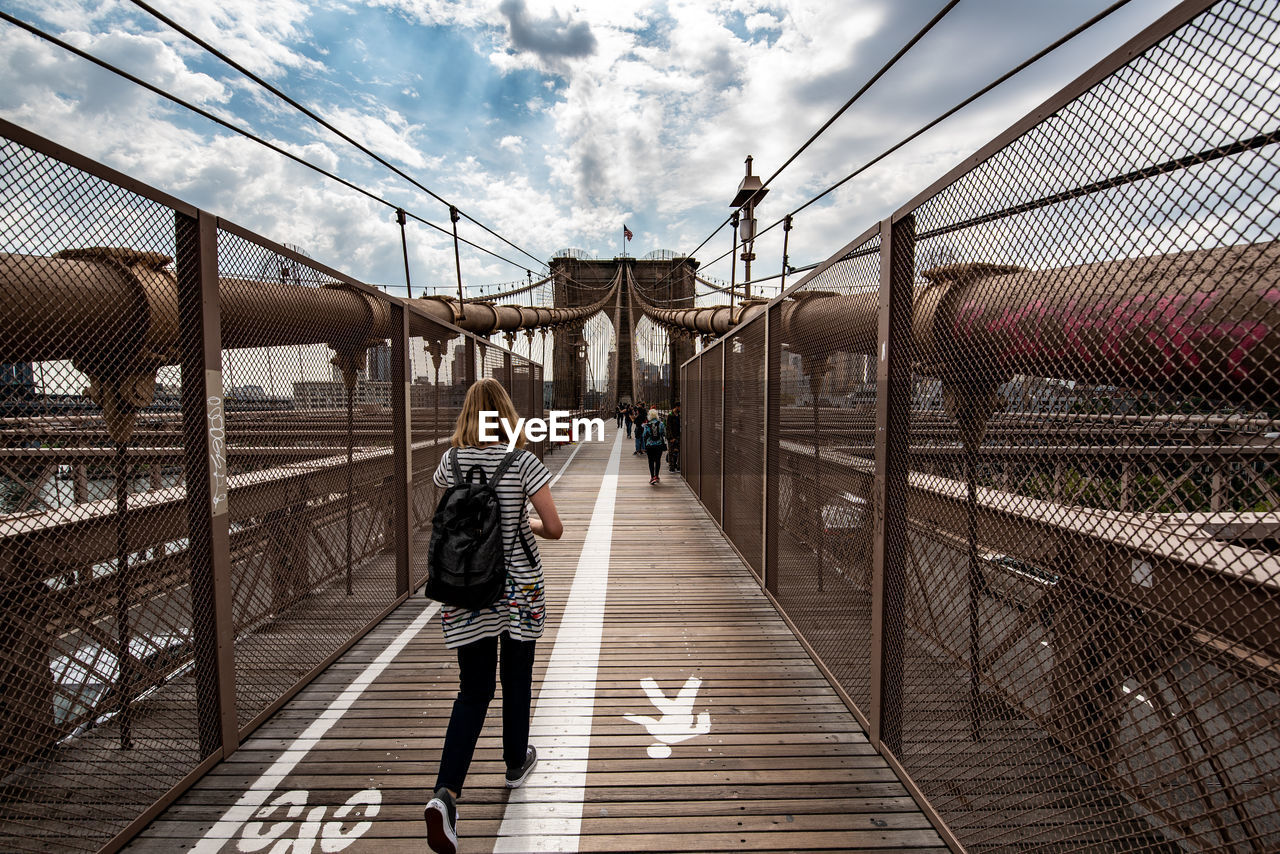 Rear view of woman walking on footbridge