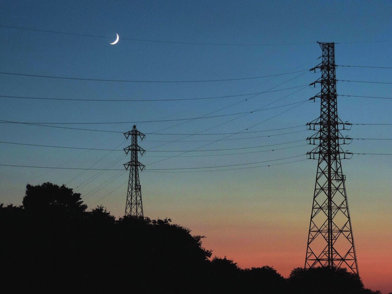 Low angle view of silhouette electricity pylon against moon in sky at dusk