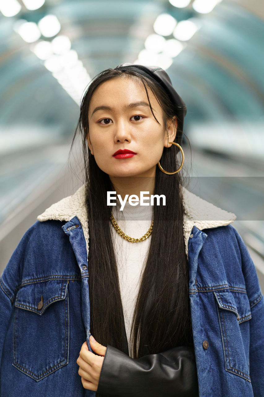 Urban fashion portrait of chinese hipster girl ride escalator to subway. lifestyle and modern trend
