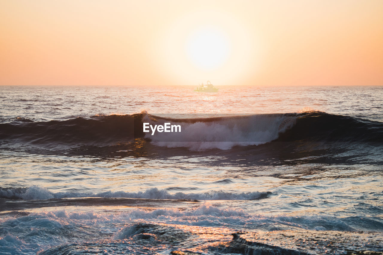 Scenic view of sea waves at sunset