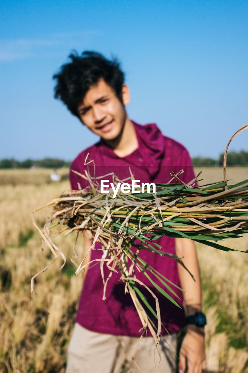 Smiling boy standing on field against grass