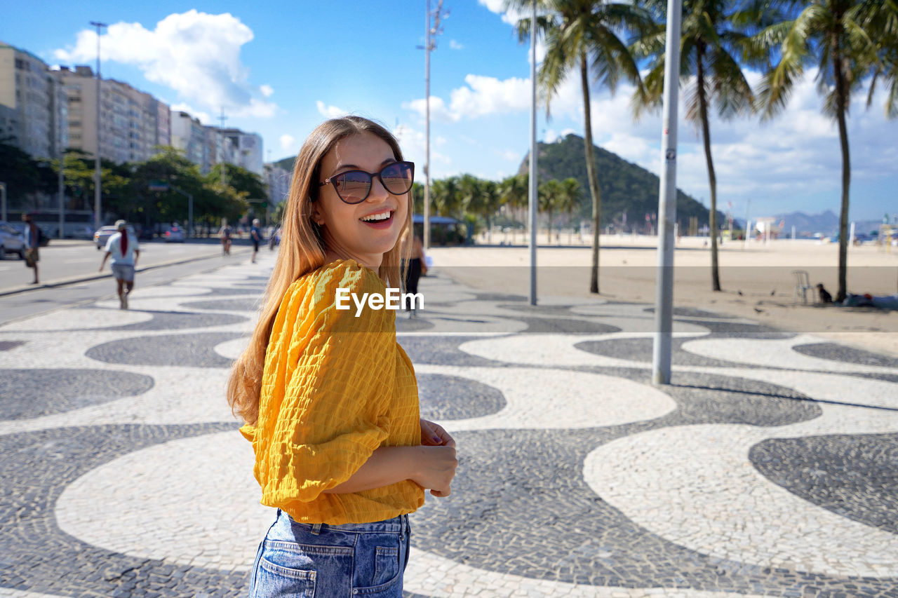Portrait of attractive smiling woman walking along copacabana beach promenade rio de janeiro, brazil