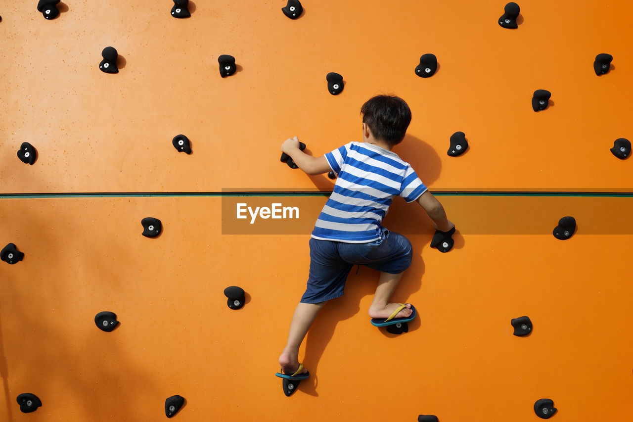 Rear view of boy climbing wall