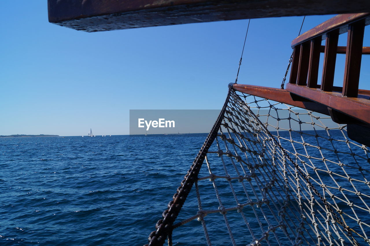 LOW ANGLE VIEW OF SAILBOAT IN SEA AGAINST CLEAR BLUE SKY