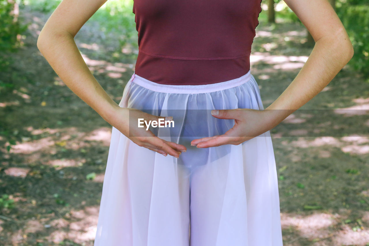 Midsection of woman doing ballet dance on field