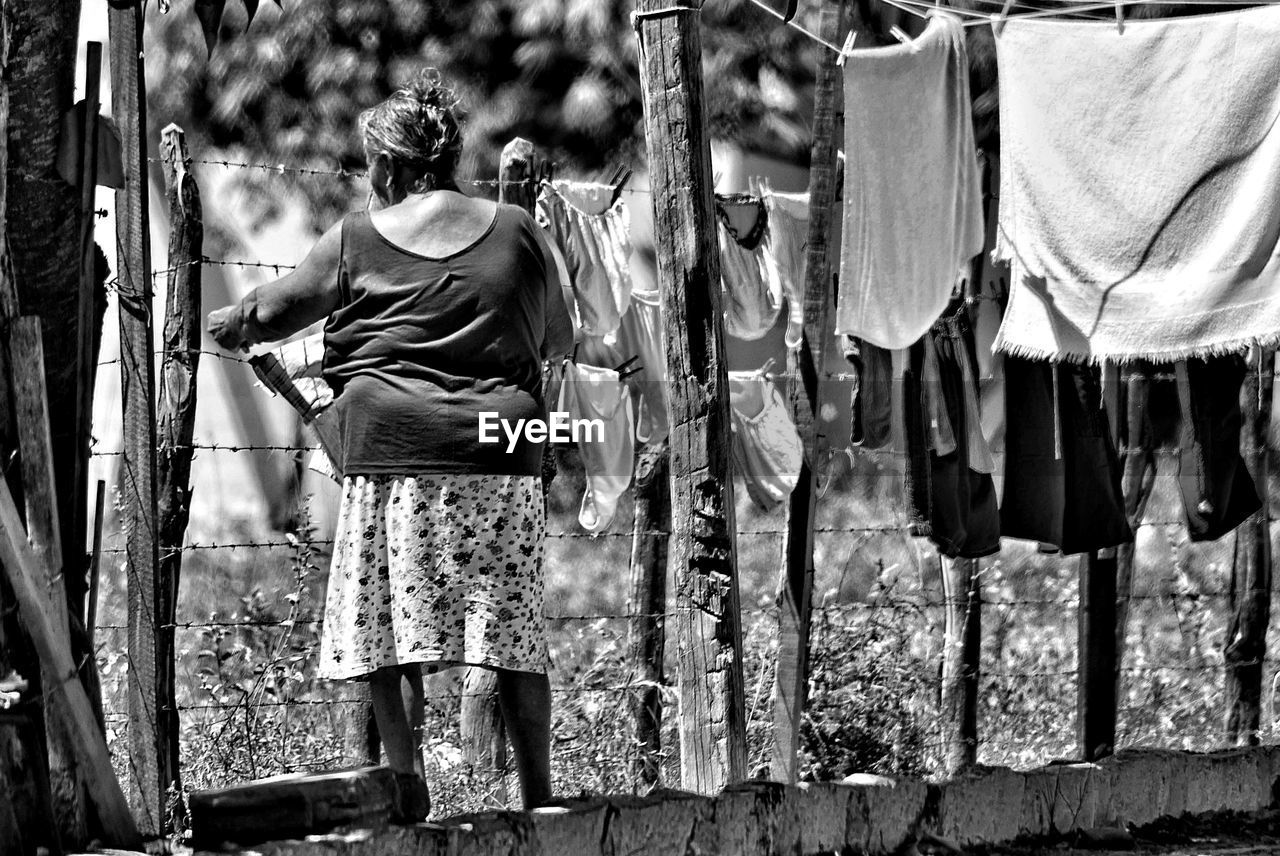 Woman hanging laundry on barbed wire fence