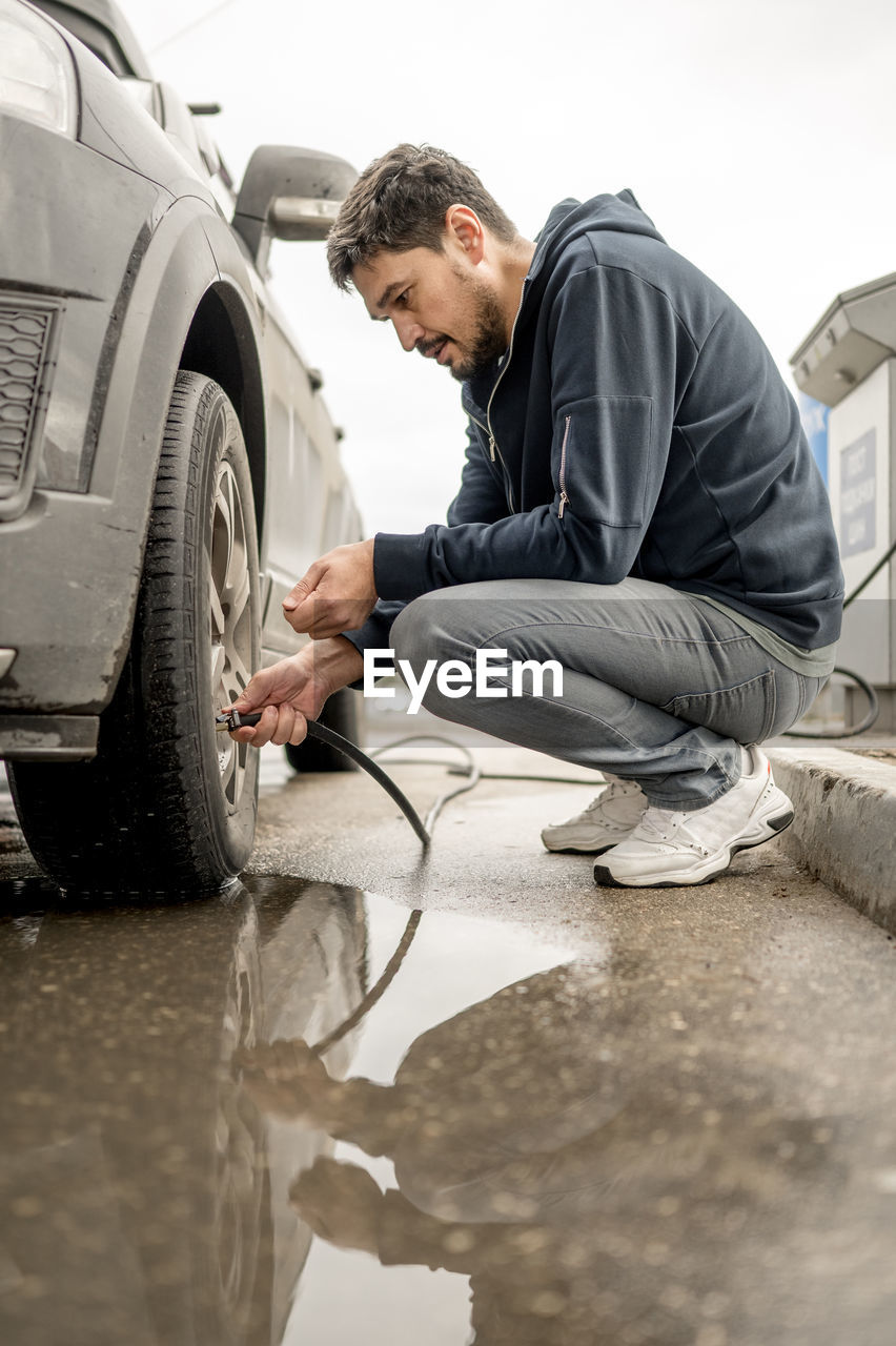 Man filling air in tire at gas station