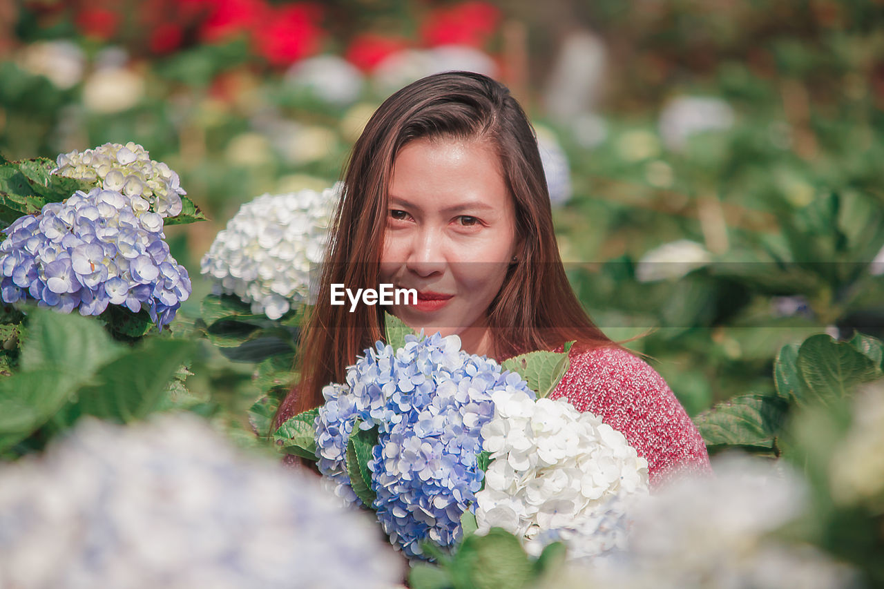 Portrait of smiling woman by flowering plants