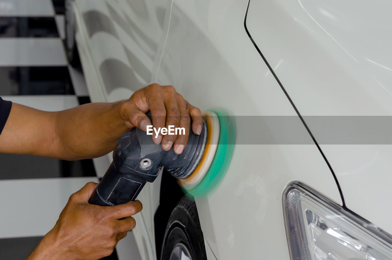 Close-up of mechanic polishing car in garage