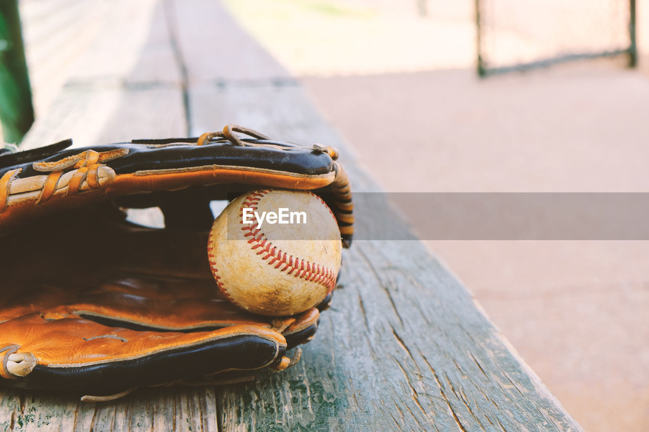 Close-up of glove and ball on wooden table