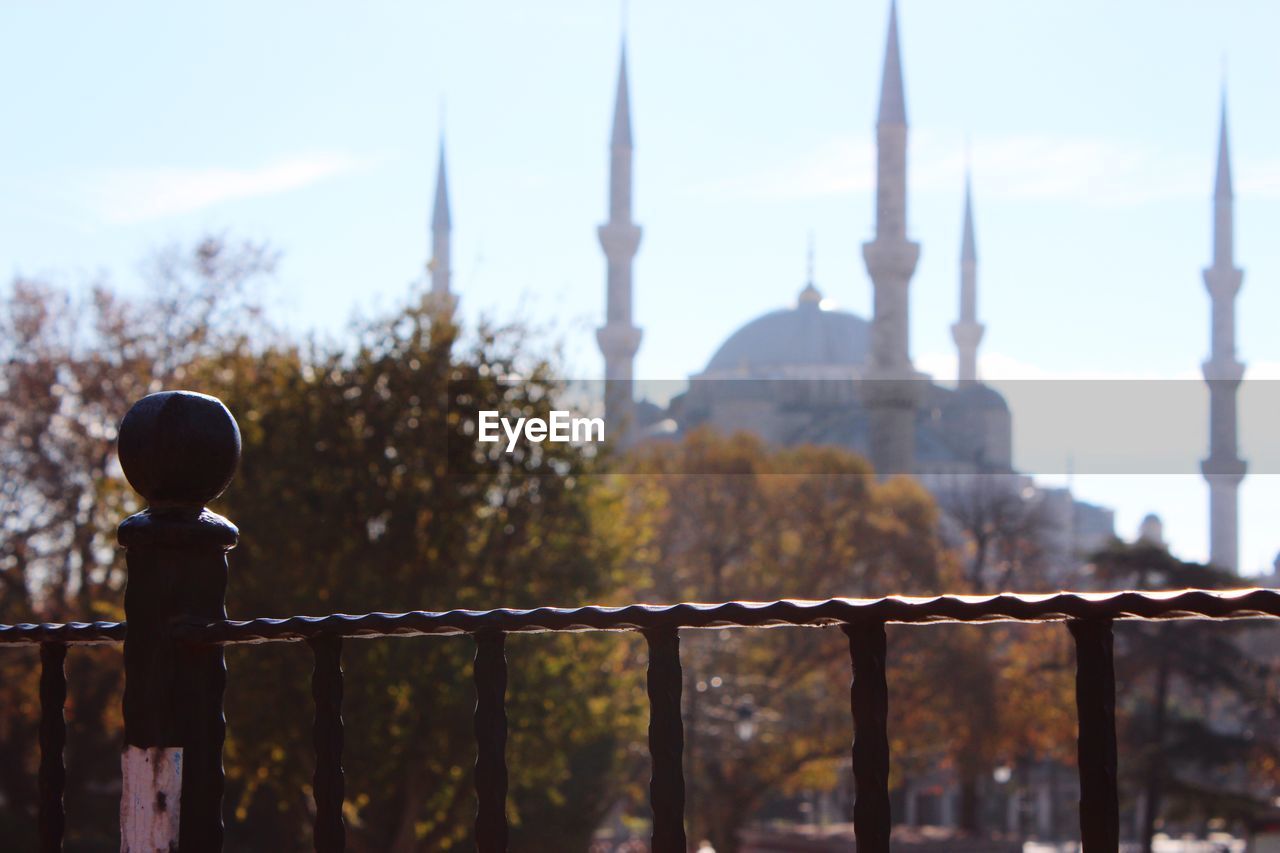 Close-up of railing with mosque against the sky